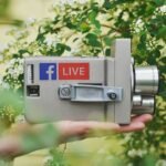 person holding gray video camera near green leaf plant during daytime